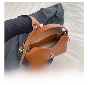 Vue intérieure du sac en cuir marron montrant le compartiment spacieux et le fermoir argenté