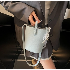 Detail of light blue bucket bag showing lychee grain leather texture and pearl charm