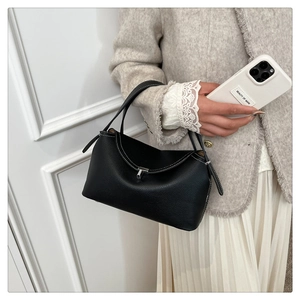 Détail du sac à main en cuir grainé noir avec surpiqûres blanches et fermoir en métal