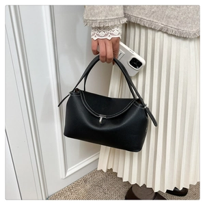 Détail d'un sac à main en cuir noir avec coutures contrastées et fermoir argenté