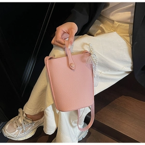 Pink bucket bag with lychee pattern leather featuring elegant pearl and lace charm details