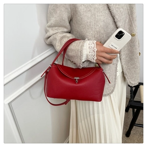 Détail du sac en cuir rouge avec coutures blanches et fermoir argenté sur tenue en tweed