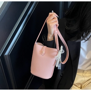 Detailed shot of pink textured bucket bag featuring pearl charm and lace bow ornament