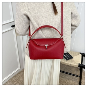 Détail du sac à main en cuir rouge grainé avec fermoir argenté et surpiqûres blanches