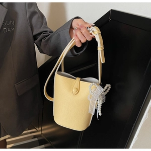 Detail of yellow bucket bag featuring lychee texture leather and elegant pearl charms