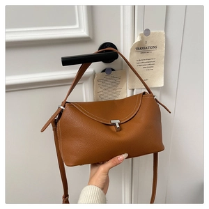 Détail d'un sac à main marron en cuir grainé suspendu à une poignée de porte