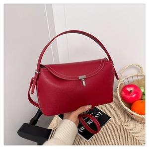 Détail du sac à main rouge en cuir grainé avec boucle argentée et couture blanche