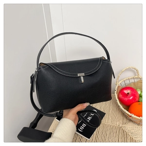 Détail d'un sac à main en cuir noir avec surpiqûres blanches et fermoir en T argenté