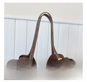 Dettaglio dei doppi cursori della zip su borsa a tracolla in camoscio marrone con fibbie