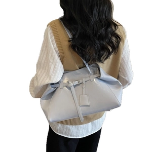 Sac à main en cuir verni bleu clair avec boucle décorative porté par un mannequin
