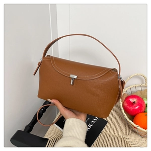 Détail d'un sac à main marron en cuir grainé avec fermoir argenté dans un décor de vie chic