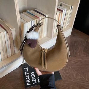 Borsa a spalla marrone stile dumpling con cerniere dorate e ciondolo a pompon decorativo