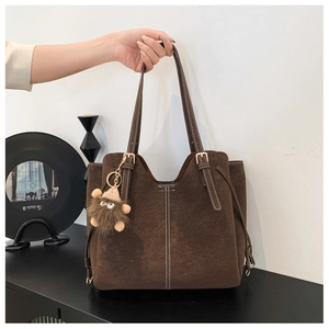 Dettaglio borsa tote in pelle opaca marrone scuro con cuciture a contrasto e ciondolo peluche