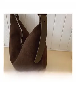 Detail of adjustable wide leather shoulder strap on deep brown suede hobo bag