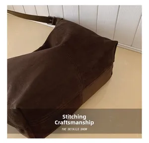Close-up of precise stitching on dark brown suede crossbody bag with metal buckle