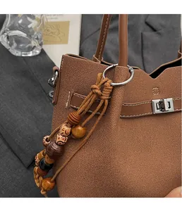 Ciondolo creativo in perle di legno su borsa in tela marrone con dettaglio chiusura in metallo