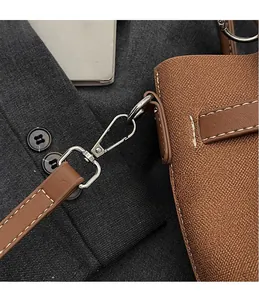 Dettaglio del gancio in metallo argento e texture pelle litchi sulla borsa marrone