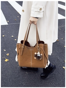 Dettaglio borsa tote in pelle scamosciata marrone con cuciture bianche e ciondolo di peluche