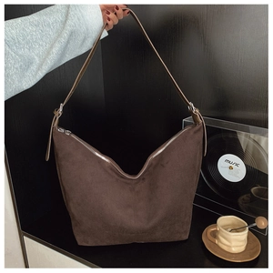 Detailed close-up of dark brown suede tote bag featuring silver metal buckle and zipper