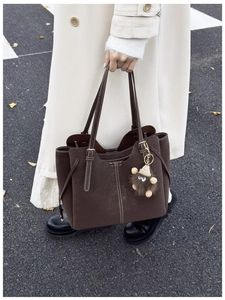Dettaglio borsa shopper marrone scuro con cuciture bianche e ciondolo in peluche moda