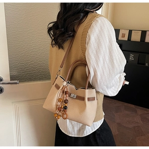 Dettaglio della borsa in pelle scamosciata beige con nappa in legno vintage e chiusura argento