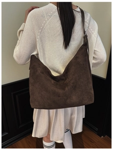 Detail of dark brown suede hobo bag texture and wide strap on a model's shoulder