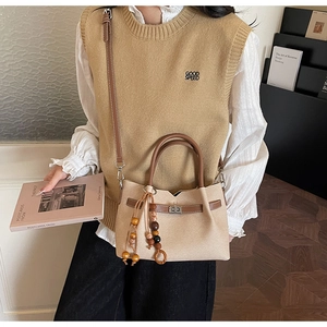 Dettaglio borsa a tracolla vintage in camoscio con cinturino in pelle e nappa in legno