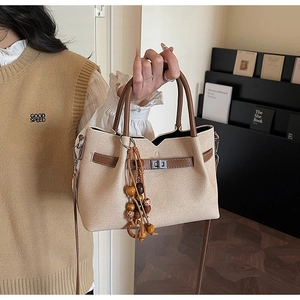 Dettaglio della borsa vintage in tela con finiture in pelle marrone e ciondolo etnico