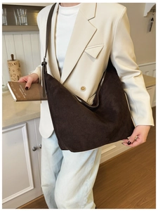 Detail shot of a dark brown suede crescent bag featuring a sleek metal zipper and slim strap