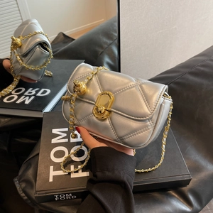 Silver quilted chain shoulder bag with gold sphere buckle and twist lock on a fashion book