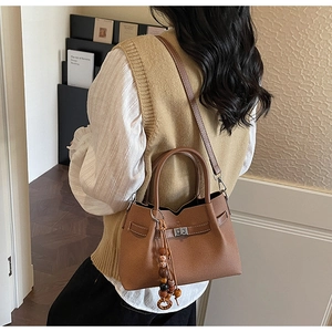 Vista posteriore di una modella con borsa marrone martellata e pendente con perle