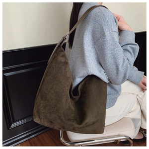Minimalist olive green suede dumpling tote bag shown worn on shoulder for daily use
