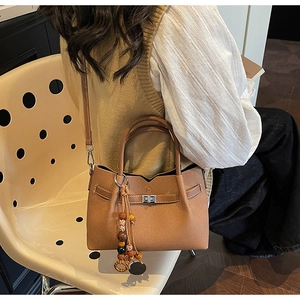 Dettaglio borsa tote in pelle scamosciata caramello con chiusura a girello e ciondolo
