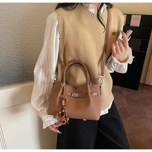 Dettaglio della borsa tote in pelle marrone scuro con grana litchi e nappa di perline