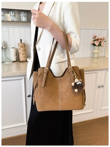 Dettaglio borsa tote in pelle scamosciata caramello con cuciture e ciondolo riccio