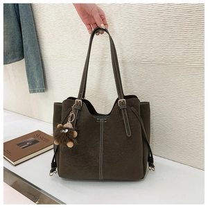 Dettaglio borsa tote in pelle scamosciata marrone scuro con cuciture bianche e charm