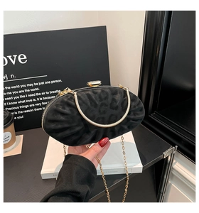 Détail de la pochette ovale noire avec texture plissée, fermoir cristal et chaîne dorée