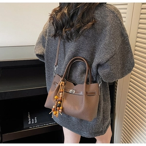 Dettaglio della borsa in pelle marrone con ciondoli in legno e chiusura girevole in metallo