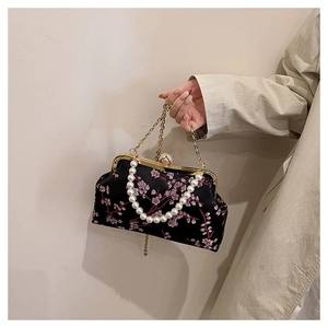 Detail of black satin evening bag with pink cherry blossom embroidery and pearl handle