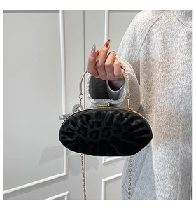 Détail de la pochette ovale noire avec poignée dorée et bandoulière chaîne pour soirée