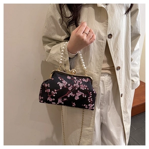 Detail of embroidered cherry blossom handbag with pearl handle and golden metal clasp