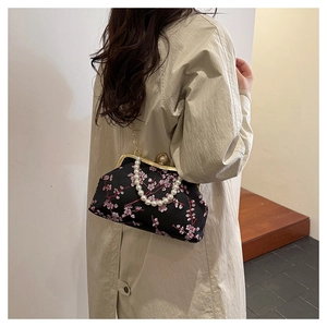 Detail of floral embroidery on black evening bag with pearl handle and metal chain