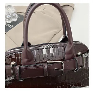 Detail shot of smooth silver-tone dual zippers on glossy brown crocodile embossed bag