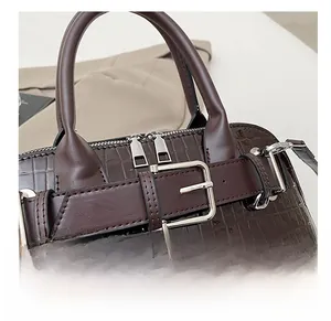 Detail of dark brown faux crocodile handbag with belt buckle and silver hardware