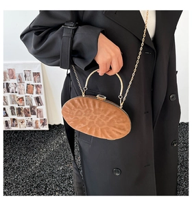 Détail de la pochette ovale marron avec poignée dorée et fermoir orné d'une pierre