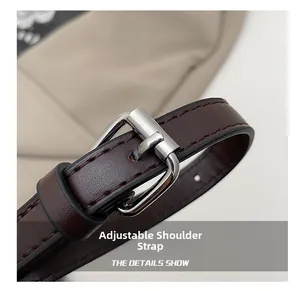 Detail of adjustable dark brown leather shoulder strap with silver buckle and stitching