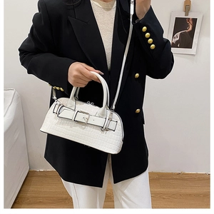 Close-up of a white crocodile pattern handbag with silver metal buckle on a model
