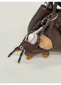 Nahaufnahme von Dackel-Anhänger aus Leder mit Baseball-Elementen an brauner Tasche