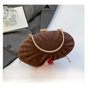 Détail de la pochette en cuir marron avec fermoir gemme et bandoulière dorée