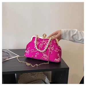 Detail of rose red silk clutch with white cherry blossom embroidery and pearl clasp